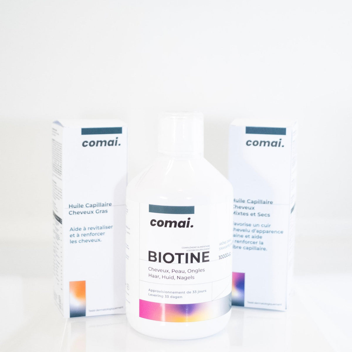 Cure 3 mois COMAI : la biotine liquide encadrée par les étuis des huiles Cheveux Gras et Cheveux Mixtes et Secs